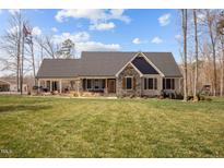 Charming home featuring a mix of stone and siding, a covered porch, and a well-manicured lawn at 1026 Burlington Rd, Roxboro, NC 27573