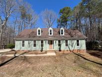 Charming one-story home with a light-green exterior, dormer windows, and beautiful lawn and surrounding trees at 1116 Shadywood Ln, Raleigh, NC 27603