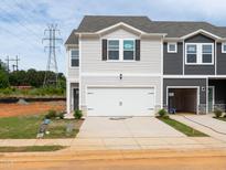 Two story townhome with a 2-car garage and light gray siding, set on a lot ready for final landscaping at 1165 Abbott St, Mebane, NC 27302
