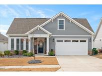 Charming home featuring gray siding, stone accents, well-manicured landscaping, and a two-car garage at 1206 Linkwood Way, Fuquay Varina, NC 27526