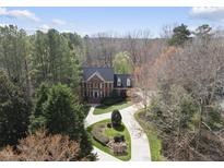 Stunning aerial view of a brick home with a circular driveway surrounded by lush greenery and mature trees at 12101 Lockhart Ln, Raleigh, NC 27614