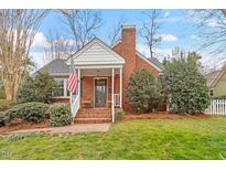 Charming brick home featuring a landscaped front yard and a welcoming front porch at 1432 Banbury Rd, Raleigh, NC 27607