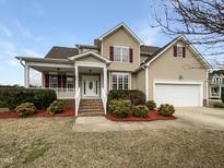 Inviting two-story home showcasing a well-manicured lawn, classic siding, and a welcoming covered front porch at 2012 Castana Ct, Willow Springs, NC 27592
