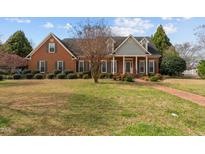Charming brick home with a well-manicured lawn, complemented by colorful landscaping at 205 Parliament Pl, Dunn, NC 28334
