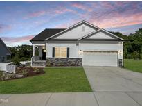 Charming single-Gathering home showcasing a well-manicured lawn, two car garage, and stone accents at 228 Pecan Valley Way, Four Oaks, NC 27524