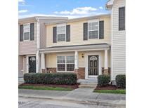 Charming two-story townhouse with yellow siding and stone accents on the front porch pillars at 5210 Blue Lagoon Ln, Raleigh, NC 27610
