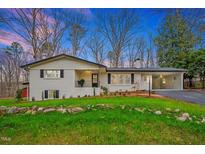 Charming home featuring a black roof, white exterior, manicured lawn, and inviting curb appeal at 605 Canterbury Rd, Sanford, NC 27330