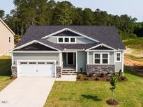 Charming one-story home featuring a two-car garage, stone accents, and fresh landscaping at 63 Tee Time Ter, Benson, NC 27504