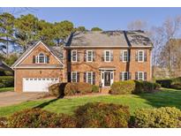 Traditional brick home with manicured lawn, lush landscaping, and attached two-car garage at 102 Ivywood Ln, Cary, NC 27518