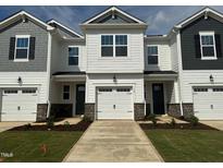 New townhomes featuring attached garages, black shutters, and light-colored siding, creating a modern and appealing facade at 18 Twin Birch Dr, Angier, NC 27501