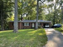 Charming brick home with mature trees, a covered carport, and a long driveway at 321 Willowood Dr, Henderson, NC 27536