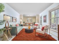Bright living room boasts a modern sofa, two chairs, large windows and a view into the formal dining room at 3613 Hope Valley Rd, Durham, NC 27707