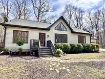 Charming one-story home featuring a landscaped front yard, a red door, and abundant natural light at 3900 Marklyn Pl, Hillsborough, NC 27278