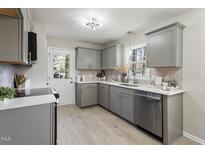 A well-lit kitchen with gray cabinetry, stainless steel appliances, and quartz countertops at 4204 Green Rd, Raleigh, NC 27604