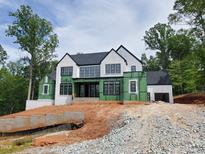 New construction home with white brick and siding, black windows, and dark roof against a lush green forest backdrop at 5808 Norwood Ridge Dr, Raleigh, NC 27614