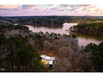 Stunning aerial view of modern home surrounded by forest and lake at sunset at 721 Jones Ferry Rd, Chapel Hill, NC 27516