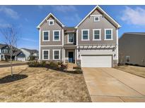 Inviting two-story home featuring a two-car garage, blue door, and a meticulously maintained landscaped front yard at 7331 Livestock Rd, Mebane, NC 27302