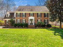 Beautiful brick home featuring black shutters, a manicured lawn and mature landscaping at 10600 Soma Ct, Raleigh, NC 27613