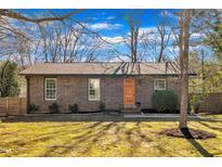 Charming brick home featuring an orange front door and manicured landscaping at 113 Ellen Pl, Chapel Hill, NC 27514