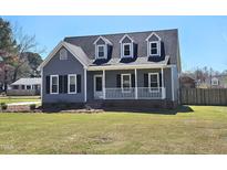 Charming home featuring a covered front porch, dormer windows, and manicured lawn at 117 Woodcroft Drive Dr, Angier, NC 27501