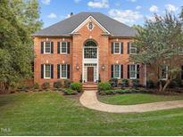 Stately two-story brick home featuring a symmetrical design, arched entry, and meticulously landscaped front yard at 12012 Six Forks Rd, Raleigh, NC 27614