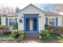 Charming home featuring a symmetrical facade with blue trim and shutters, complemented by lush, mature landscaping at 1301 Clarendon St, Durham, NC 27705