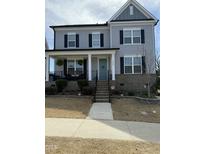 Charming two-story home with a welcoming front porch, beautiful landscaping and a blue front door at 1516 Barn Door Dr, Apex, NC 27502