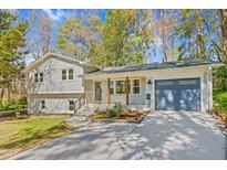 Charming home featuring a well-manicured lawn, modern garage door, and painted brick accents for a fresh, updated look at 409 Dartmouth Rd, Raleigh, NC 27609
