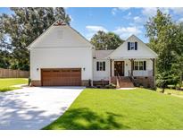Charming white exterior featuring a two-car garage, brick accents, and a well-manicured lawn under a bright blue sky at 503 Forest Rd, Oxford, NC 27565