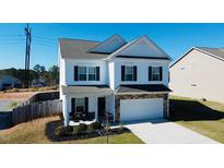 Charming two-story home featuring white siding, dark shutters, and a stone-accented garage at 612 Marian Way, Sanford, NC 27330