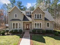 Inviting two-story home featuring a stone facade, well-manicured lawn, and mature trees at 6610 Maynard Farm Rd, Chapel Hill, NC 27516