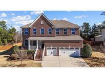 Beautiful two-story brick home with a welcoming front porch and three-car garage at 705 Prince Dr, Holly Springs, NC 27540