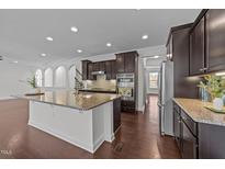 Open kitchen featuring a spacious island, granite countertops, and stainless steel appliances at 705 Prince Dr, Holly Springs, NC 27540