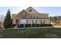 Charming two-story home with brick and stone exterior, manicured lawn, and professional landscaping at 78 Rolling Meadows Ln, Chapel Hill, NC 27517