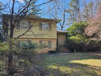 Two-story home with a brick foundation, shutters, and a lawn surrounded by trees at 939 Clarion Dr, Durham, NC 27705