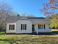 Charming single-story home with black shutters, front porch, solar panels and well-maintained lawn at 120 Keith Ct, Willow Springs, NC 27592