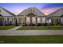Charming single-story home featuring stone accents, a welcoming front porch, and manicured landscaping at 212 Thunder Forest Ln, Wendell, NC 27591