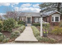 Charming brick home with a landscaped front yard and walkway leading to a teal blue front door at 411 Circle Dr, Burlington, NC 27215