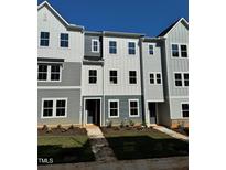 Modern townhouse exterior with gray and white siding, large windows, and well-maintained landscaping at 804 Hillfarm Dr, Wake Forest, NC 27587