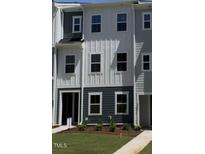 Charming townhome showcasing a modern facade with a combination of white and blue siding and freshly landscaped lawn at 804 Hillfarm Dr, Wake Forest, NC 27587