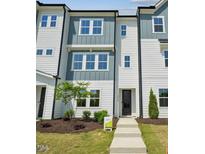 A modern, three-story townhome with a light blue and white facade, and a manicured lawn at 1028 Zelkova Ln, Chapel Hill, NC 27517