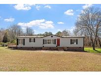 Charming single-story home with a red front door and a well-maintained lawn on a sunny day at 1425 Country Pond Ln, Willow Springs, NC 27592