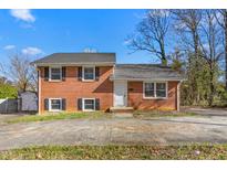 Traditional brick home with black shutters and mature trees under a bright blue sky at 1506 N Mebane St, Burlington, NC 27217