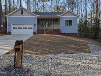 Charming single-story home with light blue siding, an attached garage, and a quaint covered front porch at 3273 Argyll Dr, Sanford, NC 27332