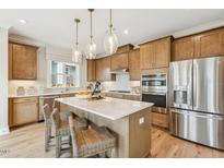 Modern kitchen features a large island with seating, stainless steel appliances, and wood cabinetry at 607 Callan View Ave, Wake Forest, NC 27587