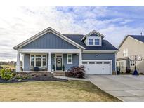 Charming home featuring a covered porch, stone accents, a two-car garage, and well-maintained landscaping at 7 Village Walk Dr, Chapel Hill, NC 27517