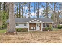 Charming single-story home featuring brick and vinyl siding, a covered porch, and mature trees in the front yard at 715 Shay Dr, Durham, NC 27704