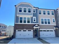 Charming townhome featuring a brick and siding exterior, complemented by a two-car garage and a well-maintained driveway at 10020 Secluded Garden Drive Rd # 188, Apex, NC 27523