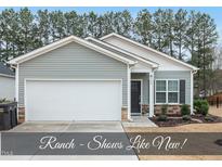 Charming ranch with gray siding, stone accents, and a two-car garage, set against a backdrop of mature trees at 175 Gill Farm Way, Franklinton, NC 27525