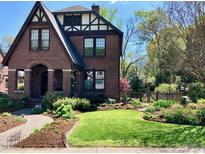 Charming brick home featuring a well-manicured lawn and lush landscaping at 1009 W Markham Ave, Durham, NC 27701